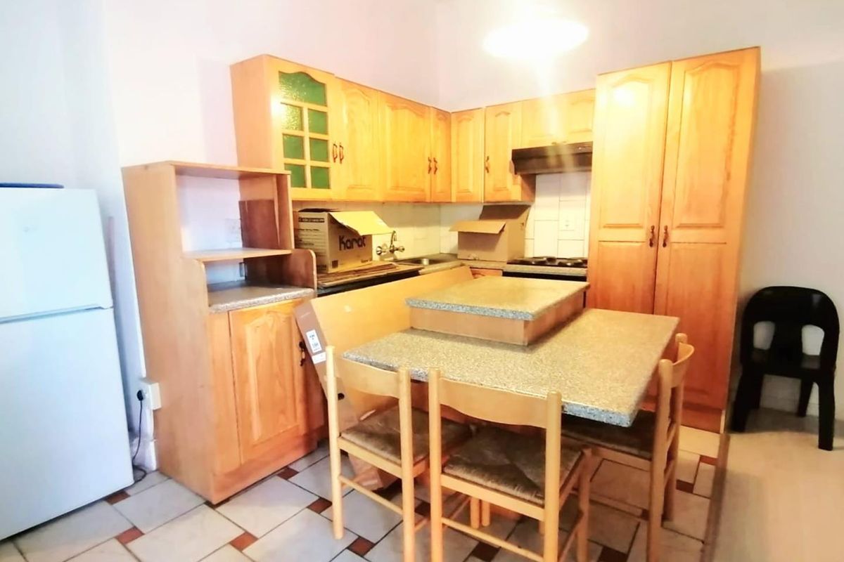A dated kitchen featuring wooden cabinetry, laminate countertops, and tiled flooring, offering potential for a modern renovation to enhance functionality and aesthetic appeal.