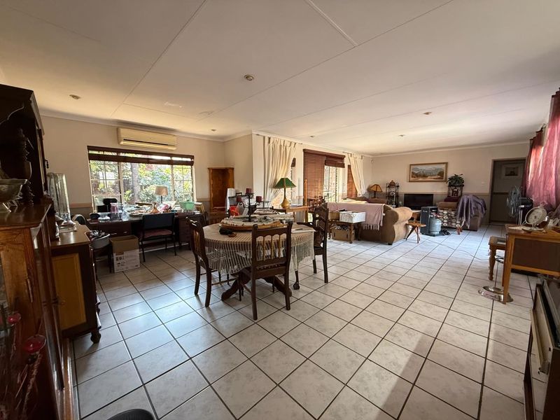 Spacious open-plan living and dining area featuring tiled flooring, recessed lighting, and a wall-mounted air conditioning unit.