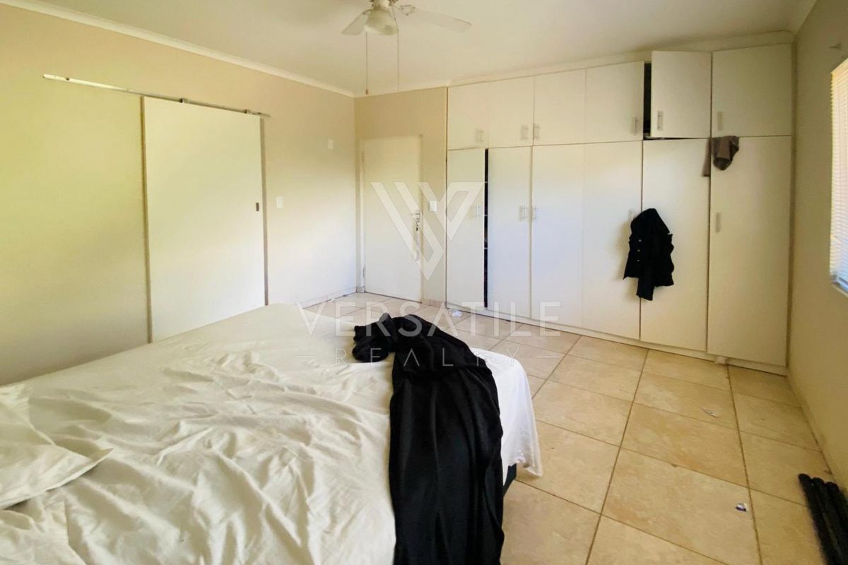 Spacious bedroom featuring built-in floor-to-ceiling wardrobes, tiled flooring, and a ceiling fan, offering a functional layout with ample storage space.