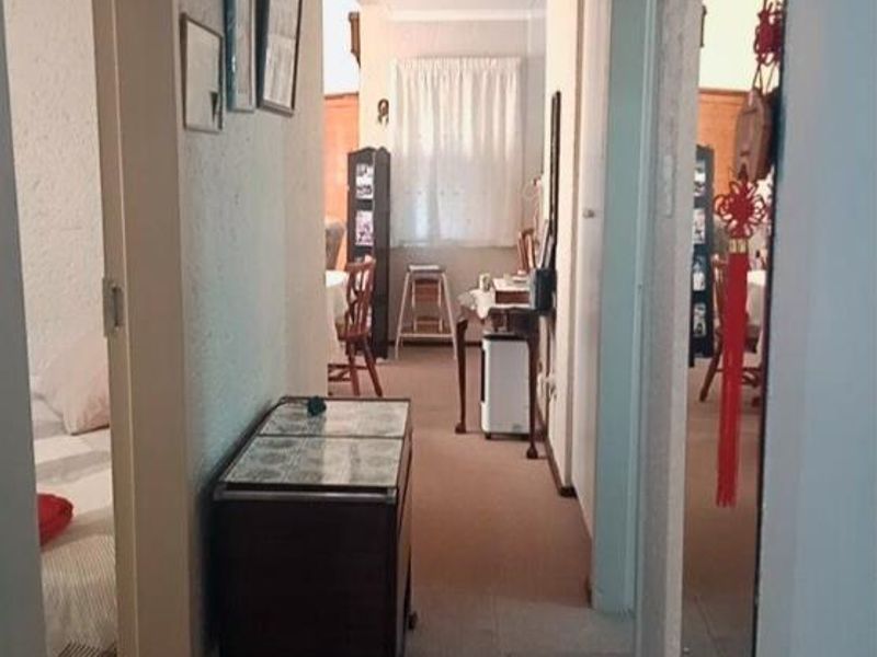 A functional residential hallway connecting multiple rooms, featuring neutral wall finishes and carpeted flooring throughout.