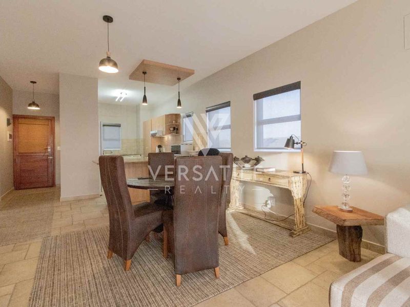 Open-plan living and dining area featuring tiled floors, modern pendant lighting, and a functional kitchen with built-in cabinetry and an island.