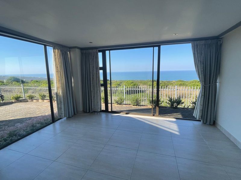 Spacious living area featuring large sliding glass doors that provide expansive ocean views and direct access to the outdoor patio.