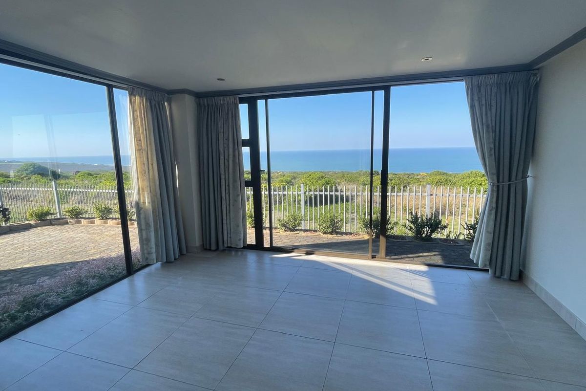 Spacious living area featuring large sliding glass doors that provide expansive ocean views and direct access to the outdoor patio.