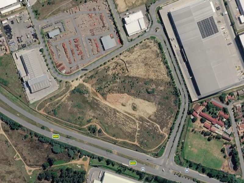 Aerial view of a large vacant commercial land parcel situated near major road infrastructure and established industrial developments.