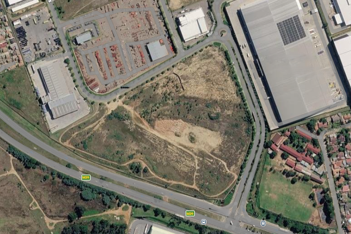 Aerial view of a large vacant commercial land parcel situated near major road infrastructure and established industrial developments.