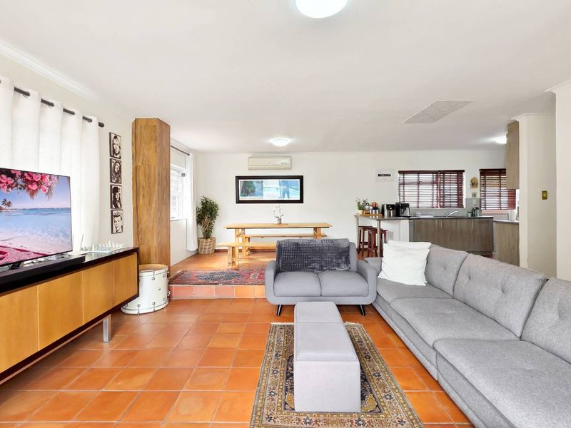Spacious open-plan living and dining area featuring terracotta floor tiles, a split-system air conditioner, and an integrated kitchen with a breakfast island.