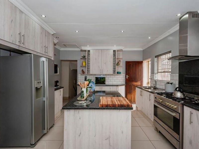Modern kitchen featuring a central island, granite countertops, stainless steel appliances, subway tile backsplash, and ample cabinetry with recessed lighting.