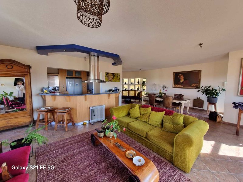 Spacious open-plan living and dining area featuring a breakfast bar, tiled flooring, and integrated display shelving.