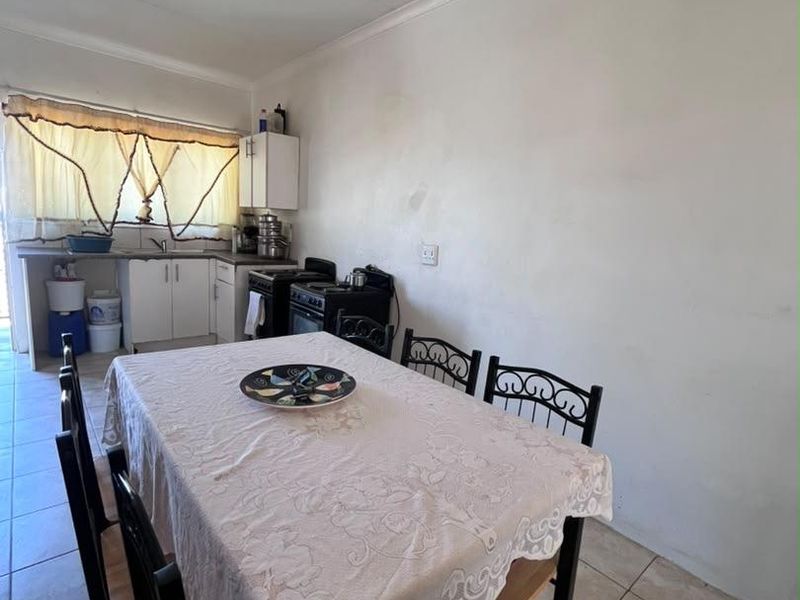 A functional kitchen area featuring tiled flooring, basic cabinetry, and a freestanding stove, offering potential for modernization and aesthetic improvement.
