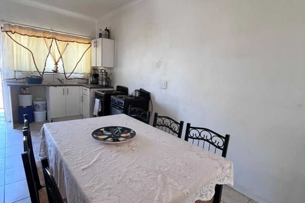 A functional kitchen area featuring tiled flooring, basic cabinetry, and a freestanding stove, offering potential for modernization and aesthetic improvement.