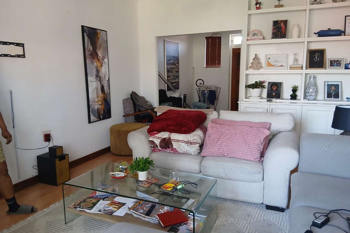 A living room featuring a large built-in shelving unit and laminate flooring, providing a functional space for relaxation and storage.