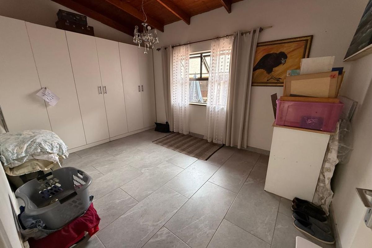 A bedroom featuring tiled flooring, exposed timber ceiling beams, and extensive built-in floor-to-ceiling cabinetry providing ample storage space.