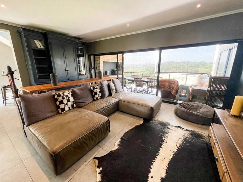 Spacious living room featuring large sliding glass doors that open to an outdoor patio, complemented by built-in cabinetry and modern tiled flooring.