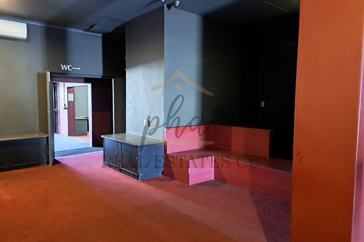 Interior view of a commercial space featuring dark walls, built-in bench seating, and access to restroom facilities.