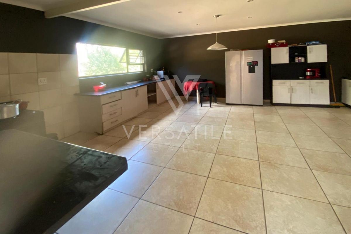 Spacious kitchen featuring tiled flooring, ample built-in cabinetry, and a large window providing natural light.