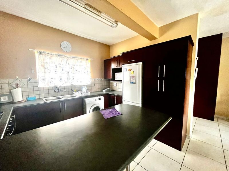 A functional kitchen featuring dark cabinetry, a breakfast bar, tiled backsplash, and tiled flooring, offering a practical layout for daily use.
