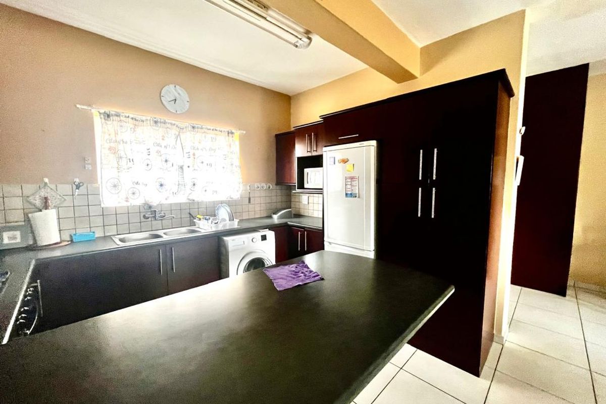 A functional kitchen featuring dark cabinetry, a breakfast bar, tiled backsplash, and tiled flooring, offering a practical layout for daily use.