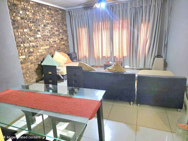 Open plan living and dining area featuring an exposed brick feature wall, tiled flooring, and a ceiling fan.
