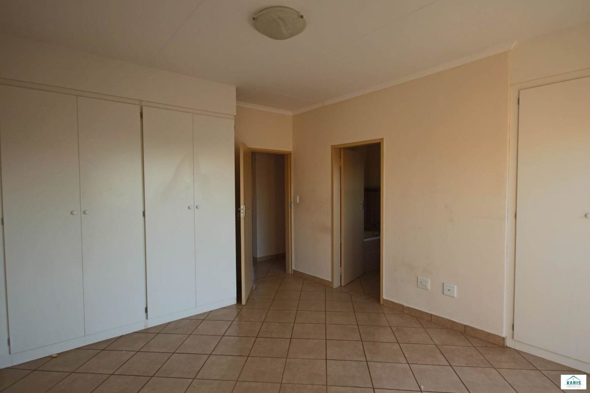 An empty bedroom featuring tiled flooring, built-in cupboards, and neutral wall finishes, providing a blank canvas for personalization.