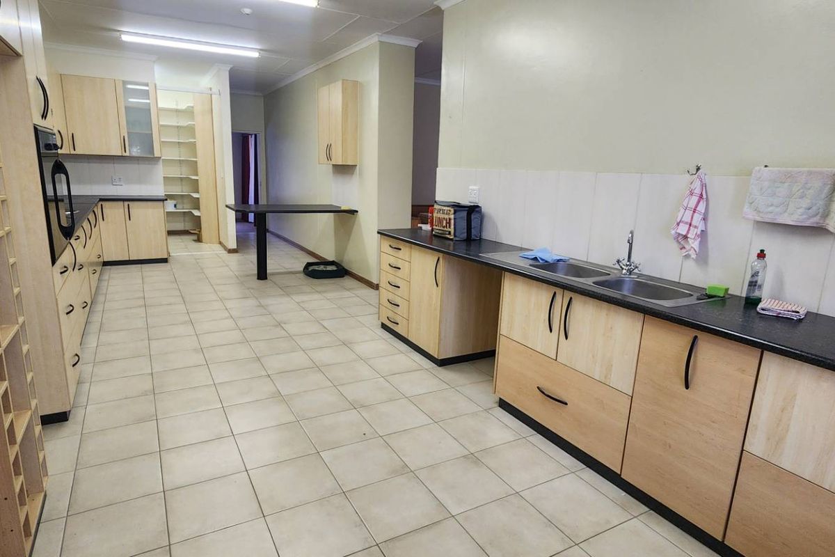 Spacious kitchen featuring extensive light wood cabinetry, dark countertops, double sink, and integrated oven, offering ample storage and workspace.