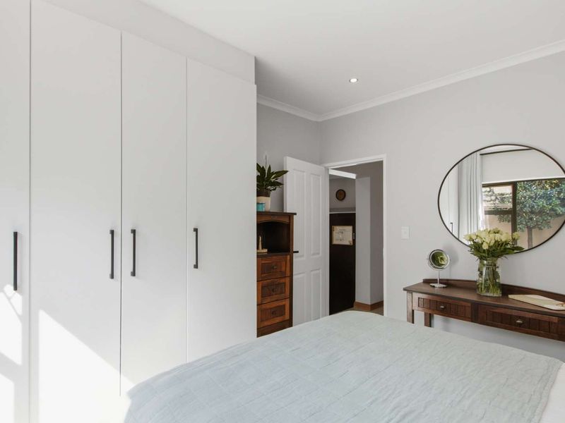 A well-maintained bedroom featuring modern built-in wardrobes, neutral wall finishes, and recessed downlighting.