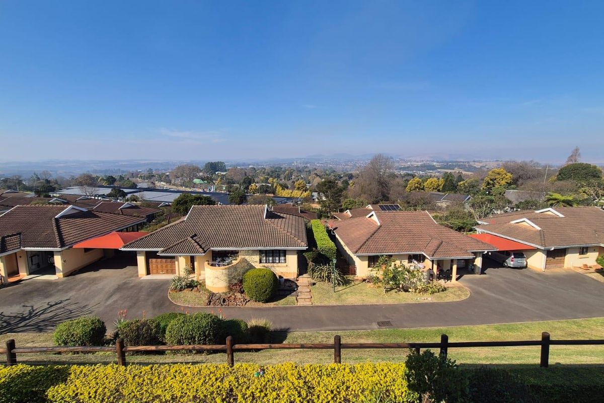 An elevated aerial view of a residential complex featuring multiple homes with tiled roofs, paved driveways, and well-maintained garden areas.