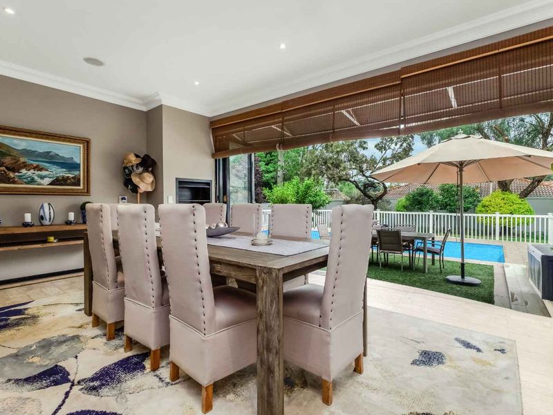 Spacious dining room featuring stone flooring, recessed lighting, and seamless indoor-outdoor flow through stacking glass doors leading to the pool area.