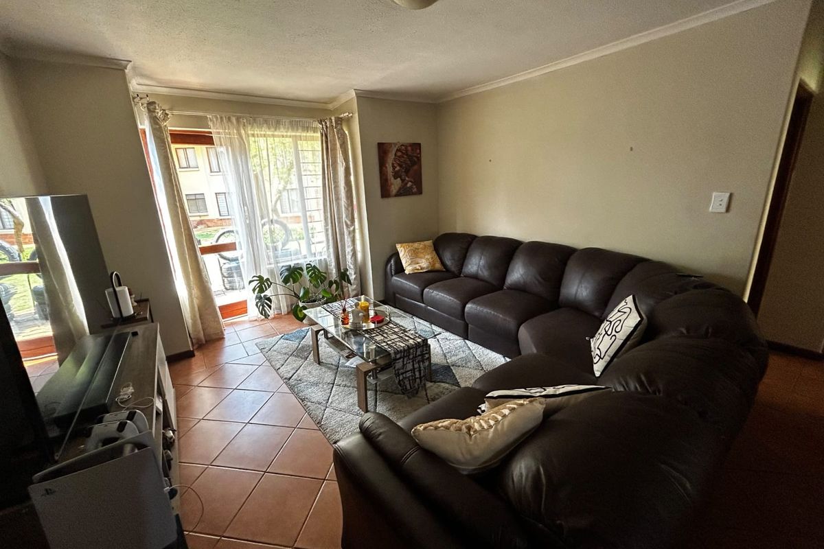 A comfortable living room featuring tiled flooring and a sliding glass door providing access to the exterior.