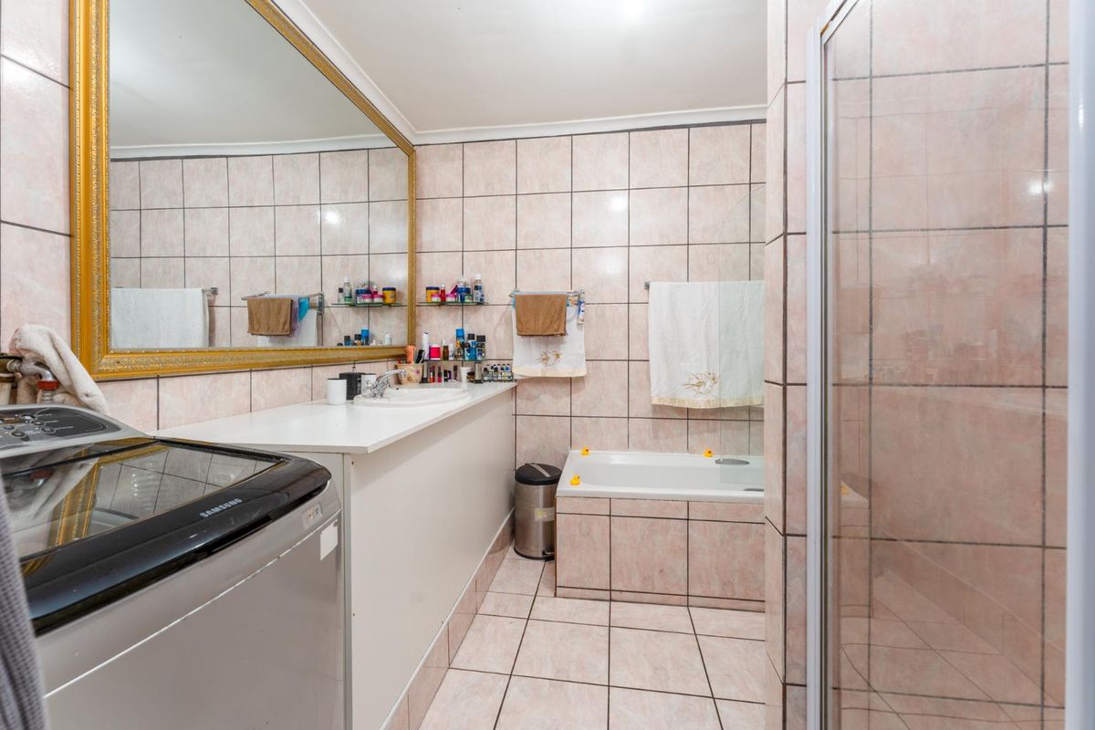 A functional bathroom featuring a built-in vanity with a large mirror, a tiled bathtub, and a separate shower enclosure with tiled finishes.