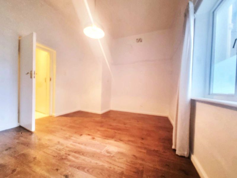 An empty bedroom featuring laminate flooring and a simple pendant light fixture, offering a blank canvas for personalization.