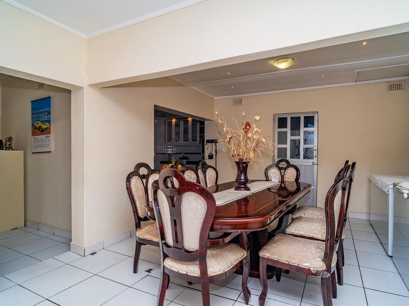 Open-plan dining area featuring tiled flooring and recessed lighting, with a direct view into the adjacent kitchen space.