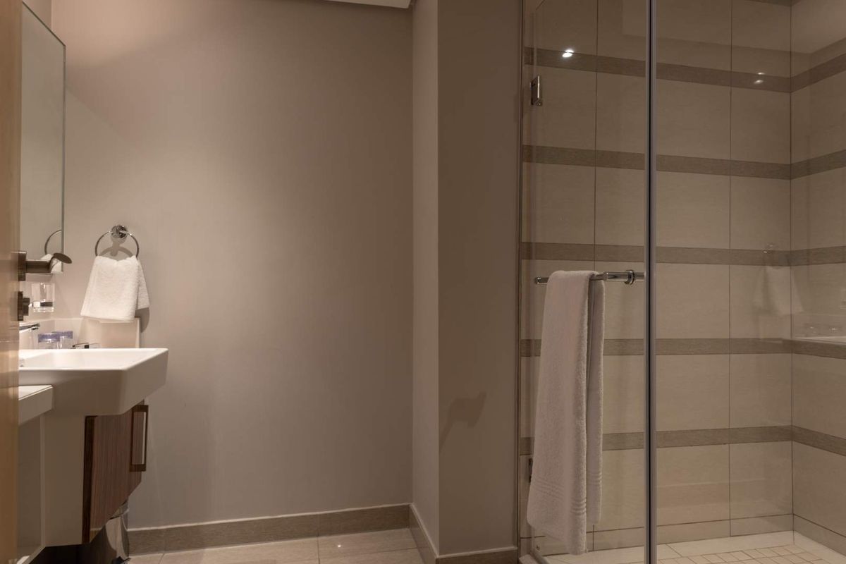 Modern bathroom featuring a glass-enclosed walk-in shower with horizontal tile accents and a wall-mounted vanity sink.