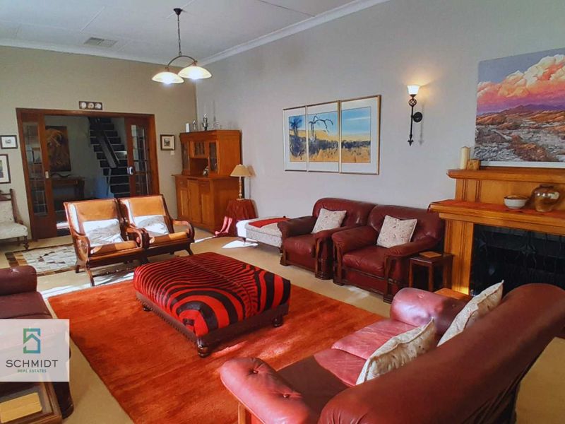 Spacious living room featuring a traditional fireplace with a timber mantelpiece, coved ceilings, and timber-framed glass doors leading to an adjacent area.