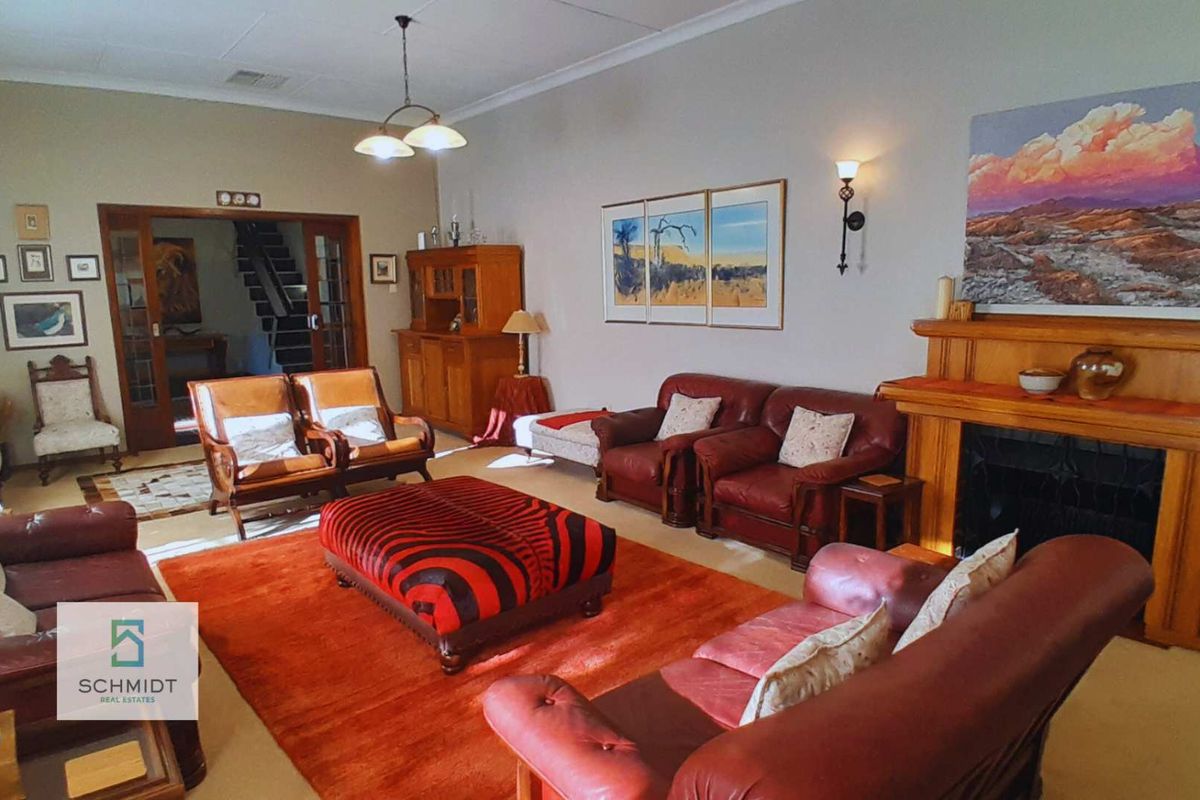 Spacious living room featuring a traditional fireplace with a timber mantelpiece, coved ceilings, and timber-framed glass doors leading to an adjacent area.
