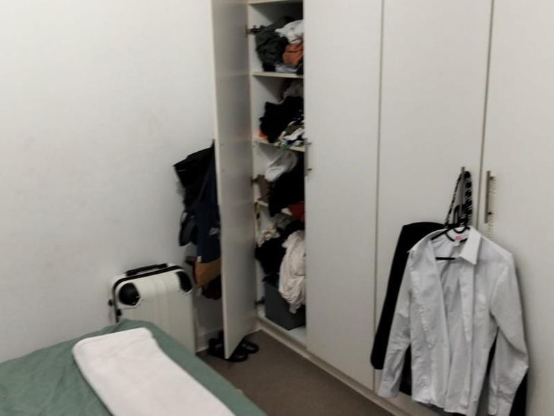 A bedroom featuring a full-height built-in wardrobe with white cabinetry.