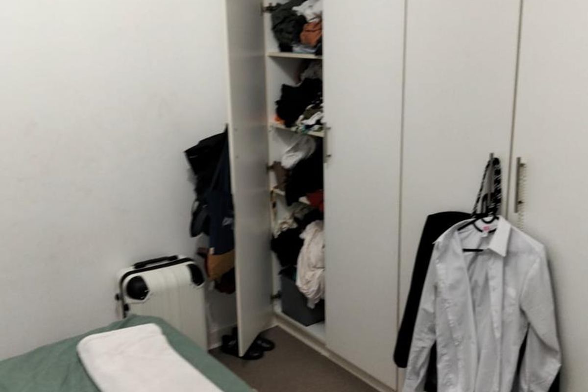 A bedroom featuring a full-height built-in wardrobe with white cabinetry.