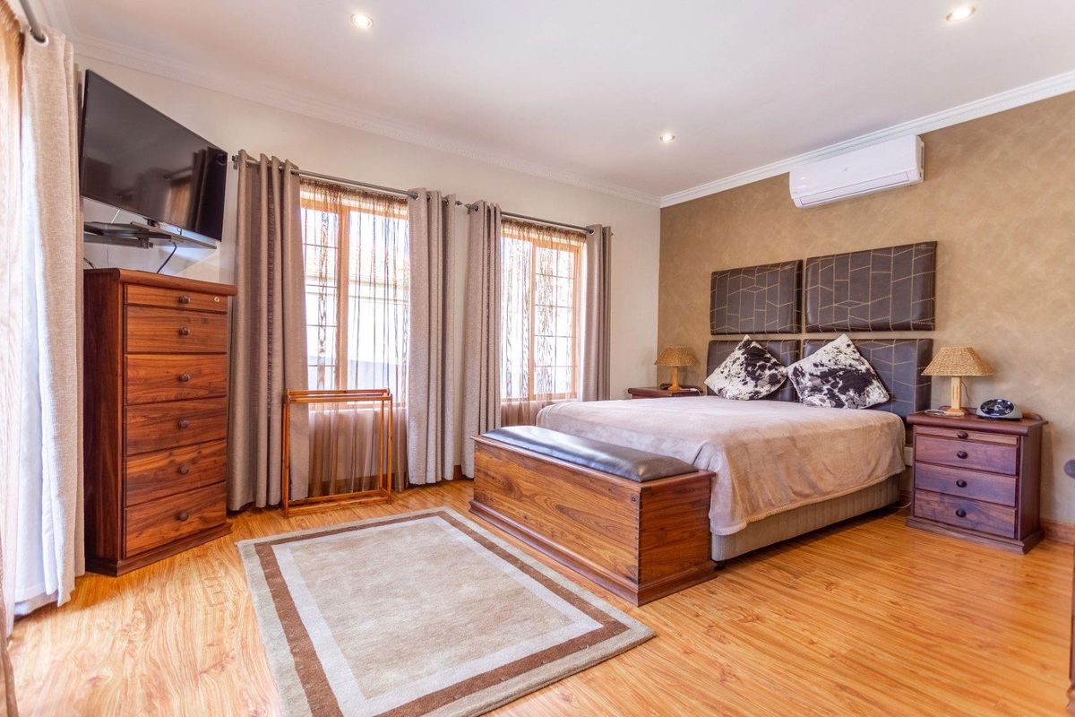 A well-maintained bedroom featuring laminate flooring, recessed ceiling lighting, and a wall-mounted air conditioning unit.