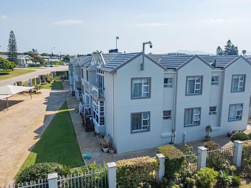 Aerial view of a multi-unit apartment complex featuring tiled roofs, paved parking areas, and well-maintained landscaped grounds.