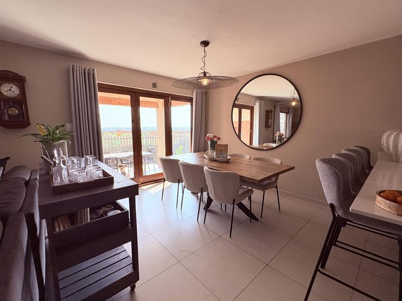An open-plan dining and living area featuring tiled floors, a breakfast bar, and large sliding glass doors that provide access to the outdoor patio.
