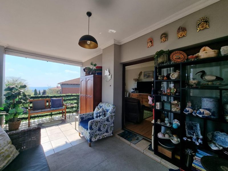 A covered balcony featuring tiled flooring, a ceiling light, and a sliding door providing access to the interior living area.