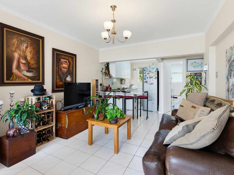 Open plan living area featuring tiled flooring and a connected kitchen with a breakfast bar, creating a functional and integrated living space.