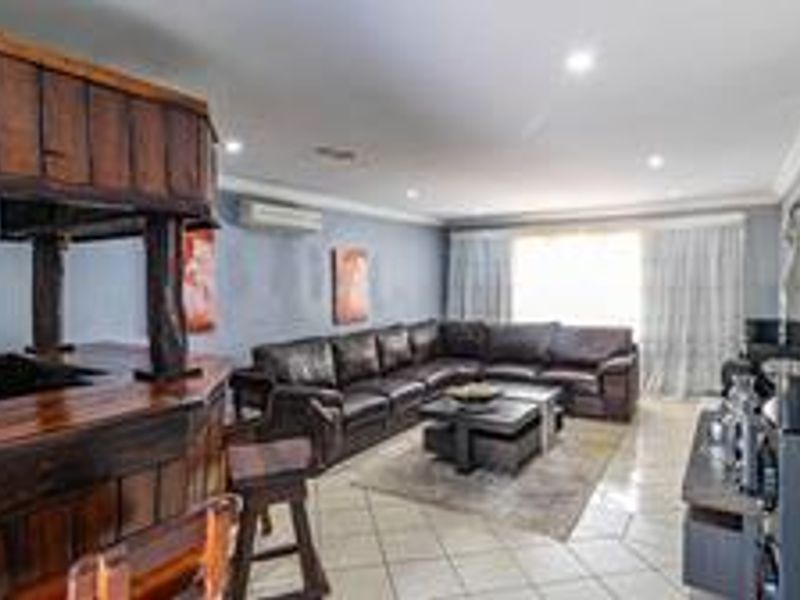 Spacious living area featuring a built-in wooden bar, tiled flooring, and split-system air conditioning, offering a functional space for relaxation and entertainment.