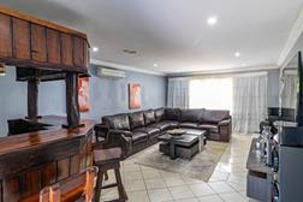 Spacious living area featuring a built-in wooden bar, tiled flooring, and split-system air conditioning, offering a functional space for relaxation and entertainment.