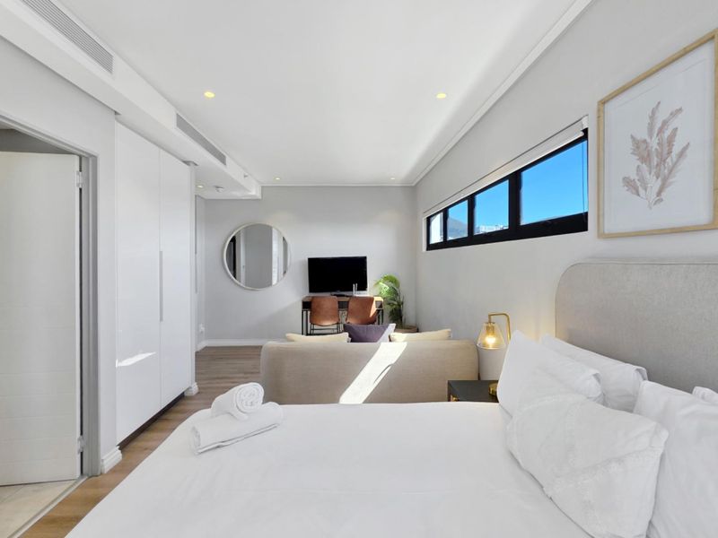 Modern bedroom featuring built-in cupboards, recessed ceiling lighting, ducted air conditioning, and horizontal clerestory windows with laminate flooring.