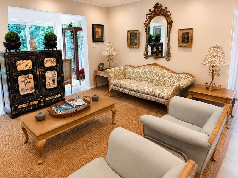 A well-maintained living room featuring neutral walls, coved cornicing, and large sliding glass doors that provide natural light and access to the garden area.