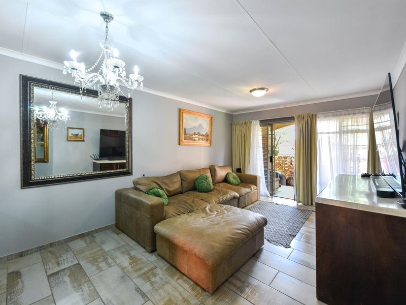 A living room featuring tiled flooring, a sliding glass door leading to the patio, and a decorative chandelier.