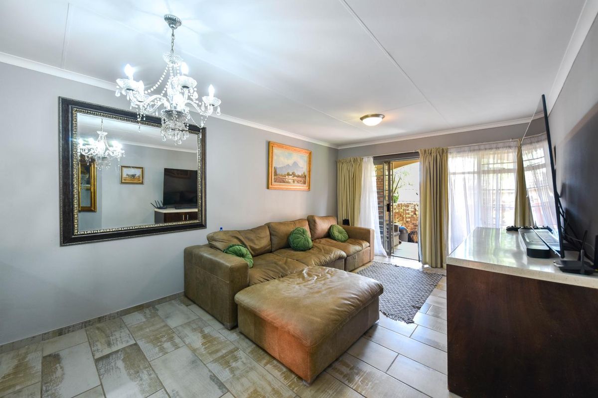 A living room featuring tiled flooring, a sliding glass door leading to the patio, and a decorative chandelier.