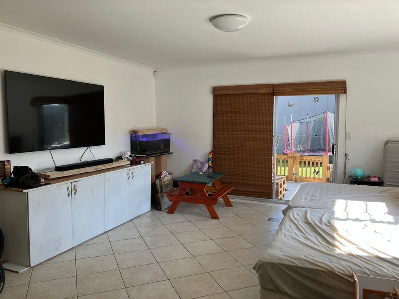 Spacious living area featuring tiled flooring, built-in storage cabinetry, and direct access to an outdoor patio through a sliding glass door.