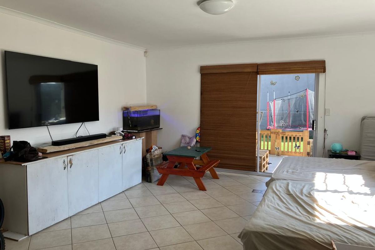 Spacious living area featuring tiled flooring, built-in storage cabinetry, and direct access to an outdoor patio through a sliding glass door.
