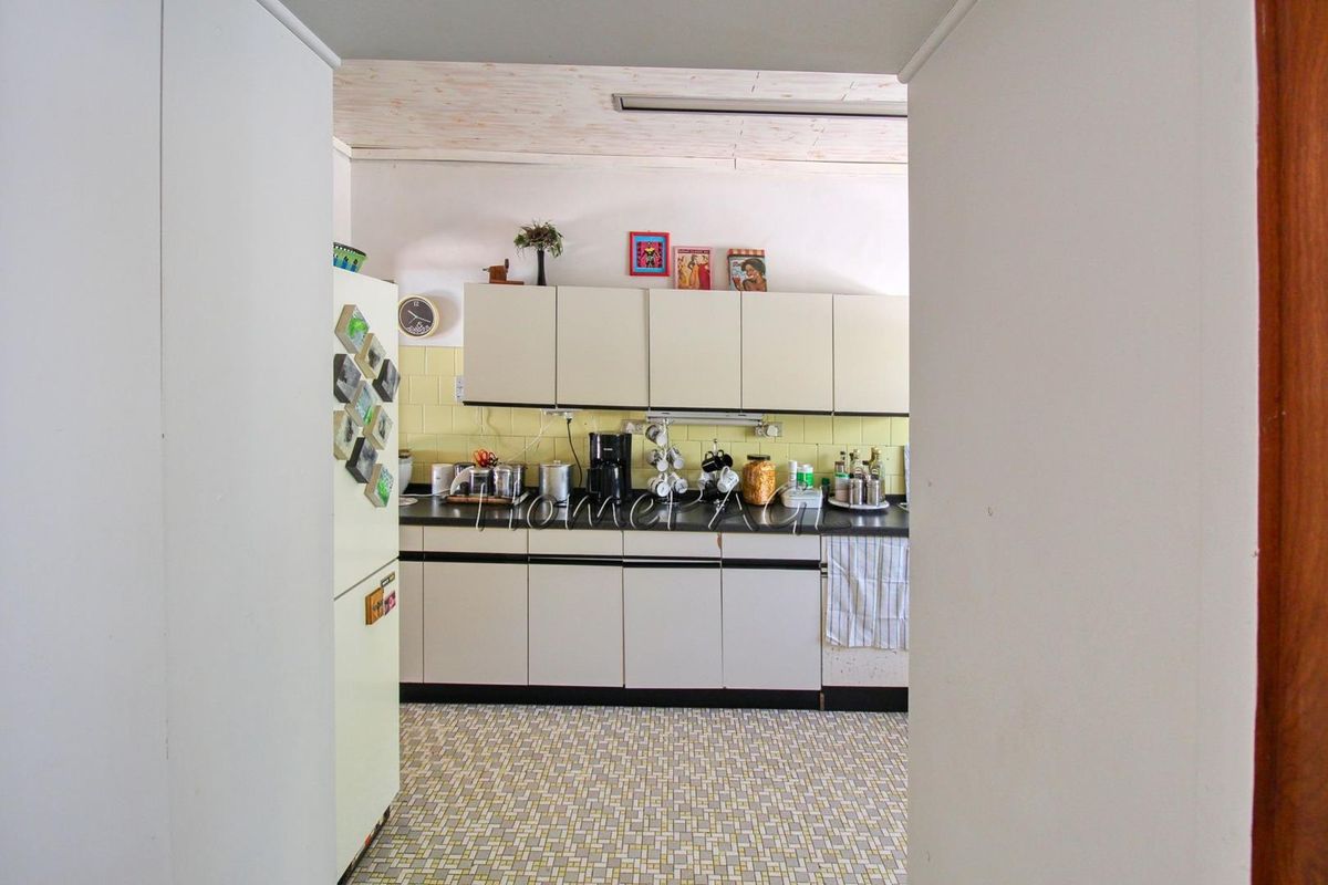 A functional kitchen featuring built-in cabinetry, a tiled backsplash, and patterned flooring, viewed through a doorway.